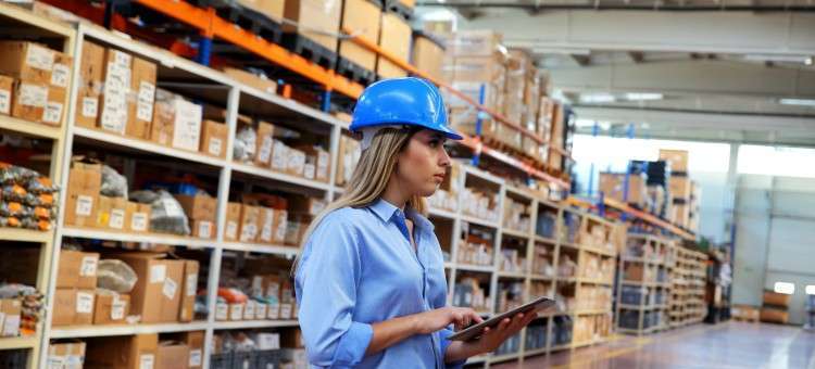 Warehouse worker in a hard hat checking inventory on a tablet