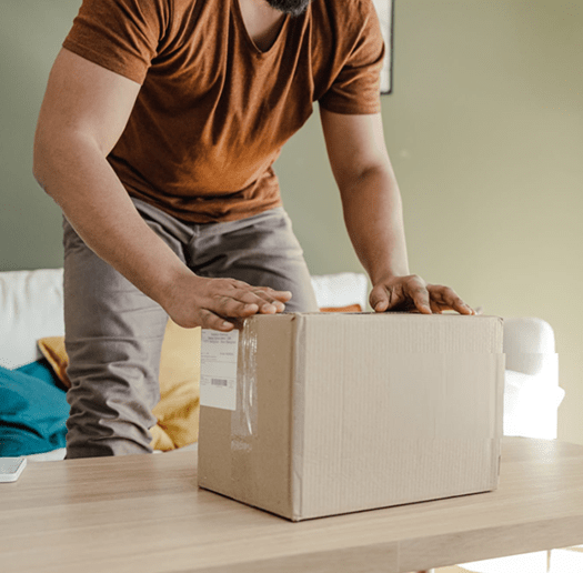 Person sealing a shipping box on a table
