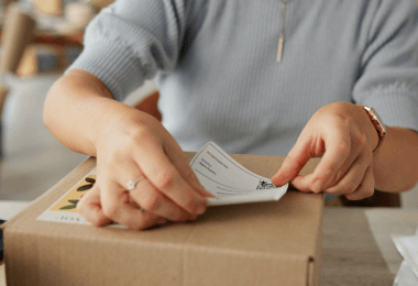 Person applying a shipping label to a cardboard box