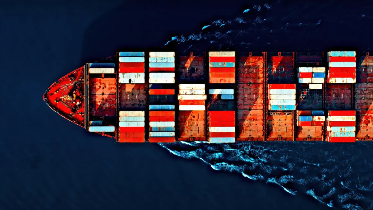 Aerial view of a cargo ship carrying colorful containers sailing through the ocean