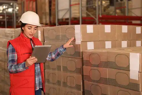 Warehouse worker reviewing stacked inventory on a tablet