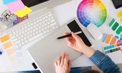 Designer using a drawing tablet next to a color wheel and swatches