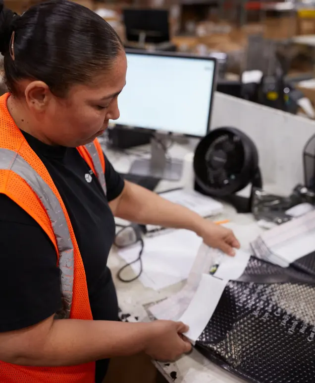 Warehouse associate reviewing packing slips at a workstation