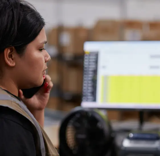 Warehouse associate on a phone call at a computer workstation