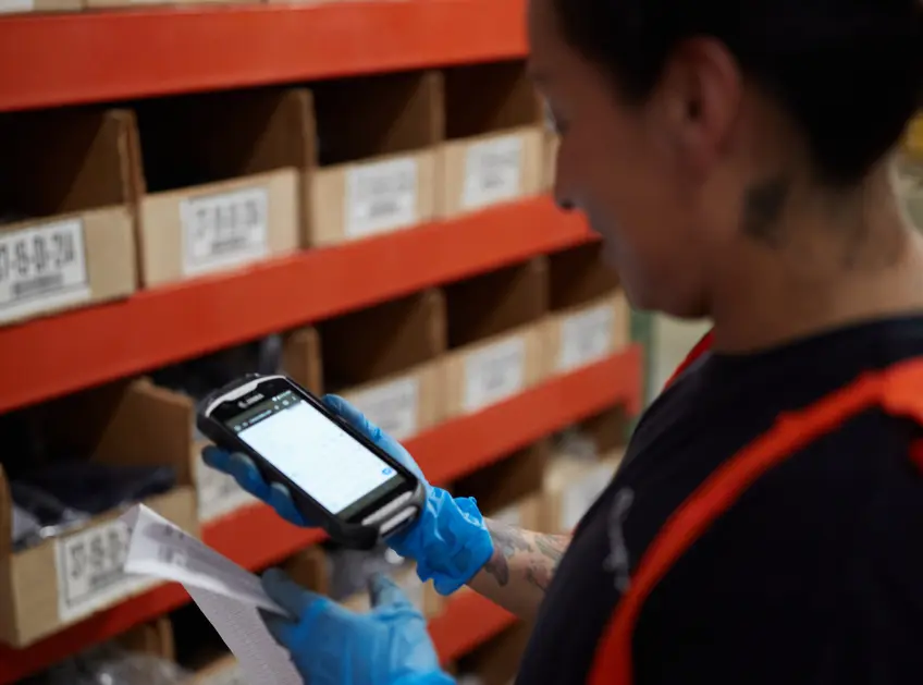Warehouse associate scanning inventory bins with a handheld scanner