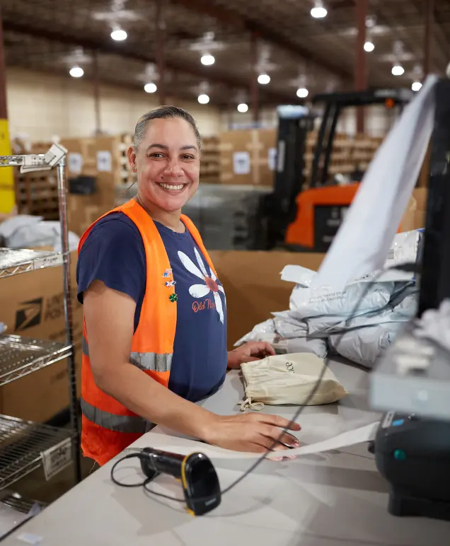 Smiling warehouse associate at a packing station