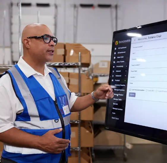 Boxzooka employee demonstrating the WMS on a wall-mounted screen