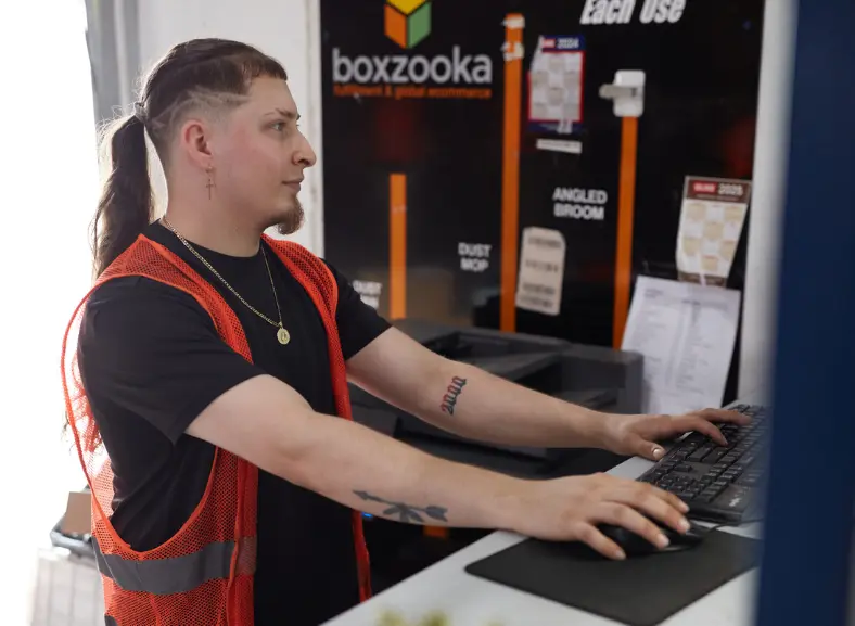 Boxzooka employee working at a computer near a branded facility sign