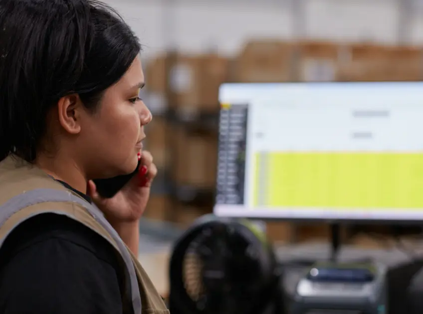 Warehouse associate on a phone call at a computer workstation