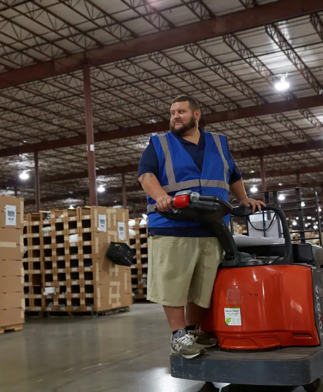 Warehouse associate operating a pallet jack in a warehouse aisle