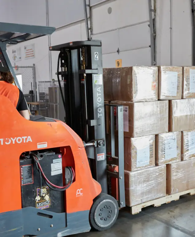 Forklift moving a pallet of wrapped boxes at a loading dock