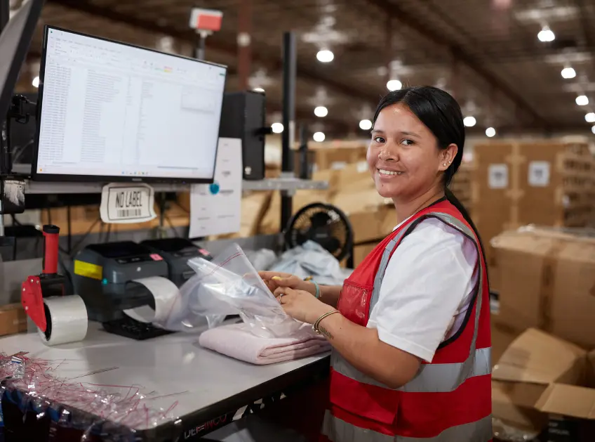 Warehouse associate smiling at a packing station computer