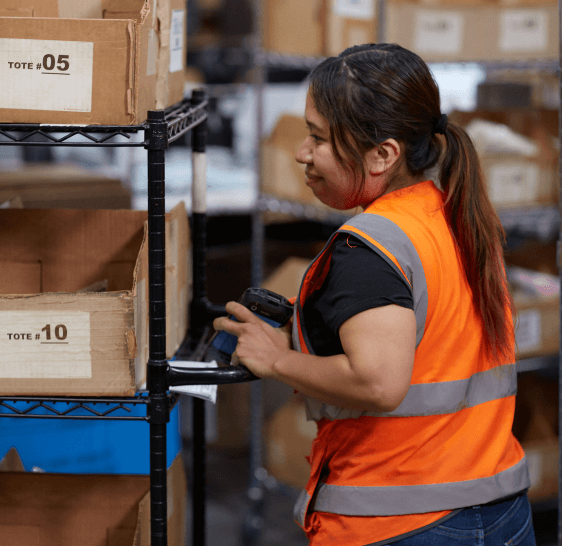 Warehouse associate scanning tote bins on a storage shelf