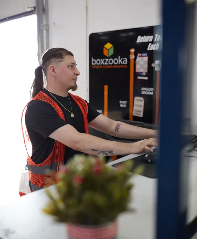 Boxzooka employee working at a computer near a branded facility sign