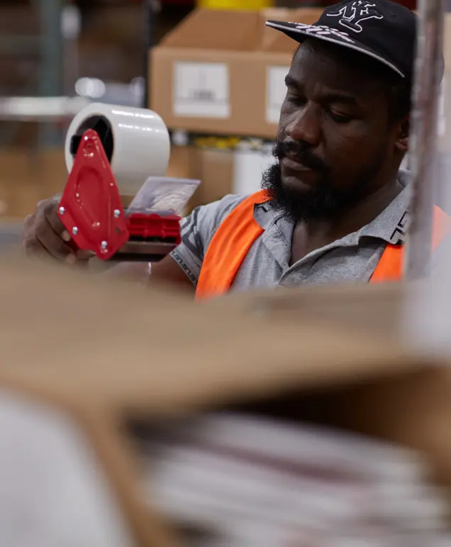 Warehouse associate taping a box shut