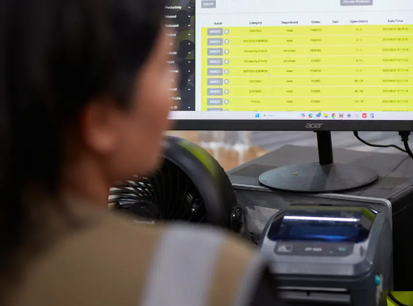 Warehouse associate reviewing order batches on a monitor