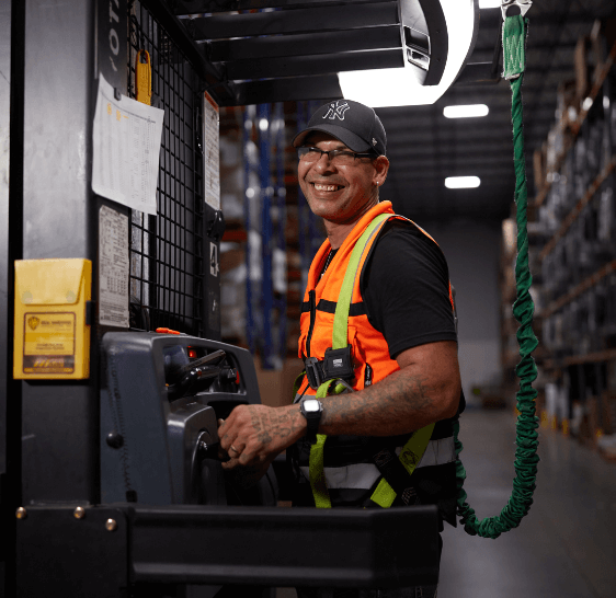 Warehouse associate smiling while operating an order picker