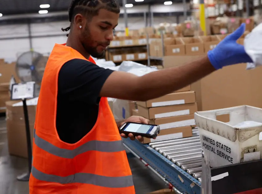 Warehouse associate sorting packages near a conveyor line