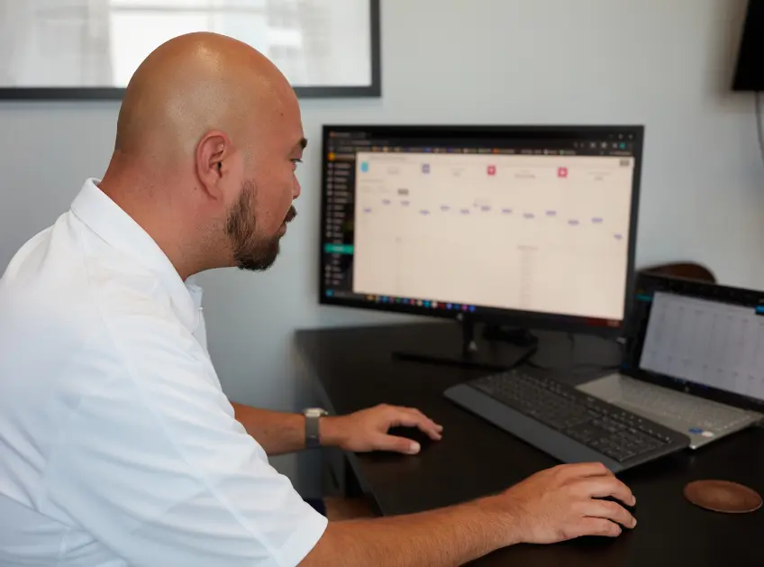 Boxzooka employee using the warehouse management system dashboard on a desktop and laptop