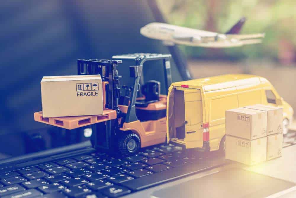 Logistics, supply chain and delivery service concept : Fork-lift truck moves a pallet with box carton. Van on a laptop computer, depicts wide spread of products around globe in ecommerce booming