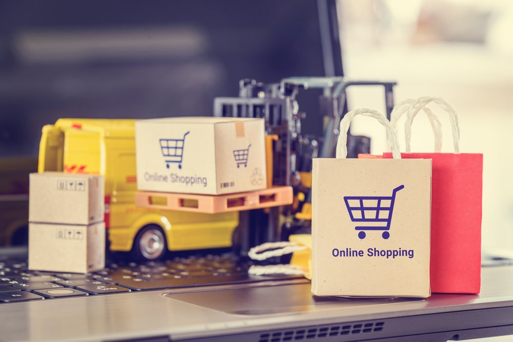 Online shopping, logistics, supply chain and shipping service, e-commerce concept : Paper shopping bags, boxes of goods, delivery van on a laptop, depicts customers use internet to order buy things