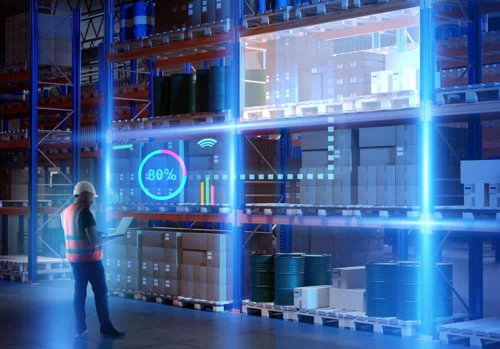 Man runs high-tech warehouse. Manager with laptop near racks of boxes. Worker stands in fulfillment center building. Director of technological warehouse. Concept of using modern warehouse software