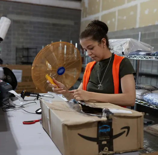 Warehouse associate opening a package at a packing station