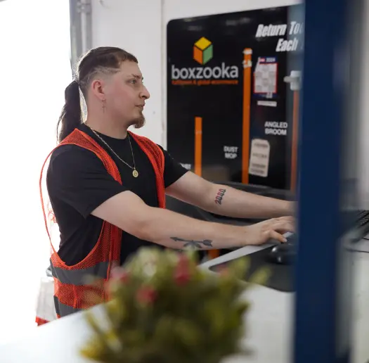 Boxzooka employee working at a computer near a branded facility sign