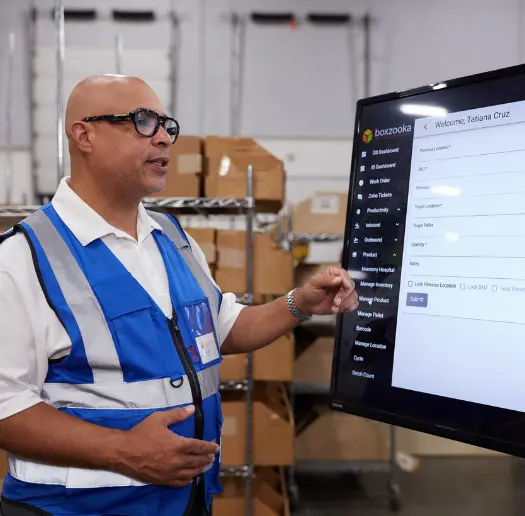 Boxzooka employee demonstrating the WMS on a wall-mounted screen