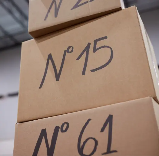 Stack of cardboard shipping boxes with handwritten numbers