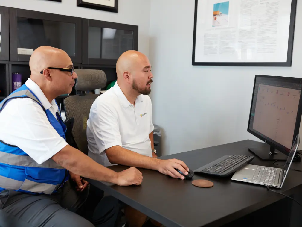 Boxzooka team reviewing transportation management system (TMS) dashboard on desktop computer, optimizing shipping routes and logistics performance.
