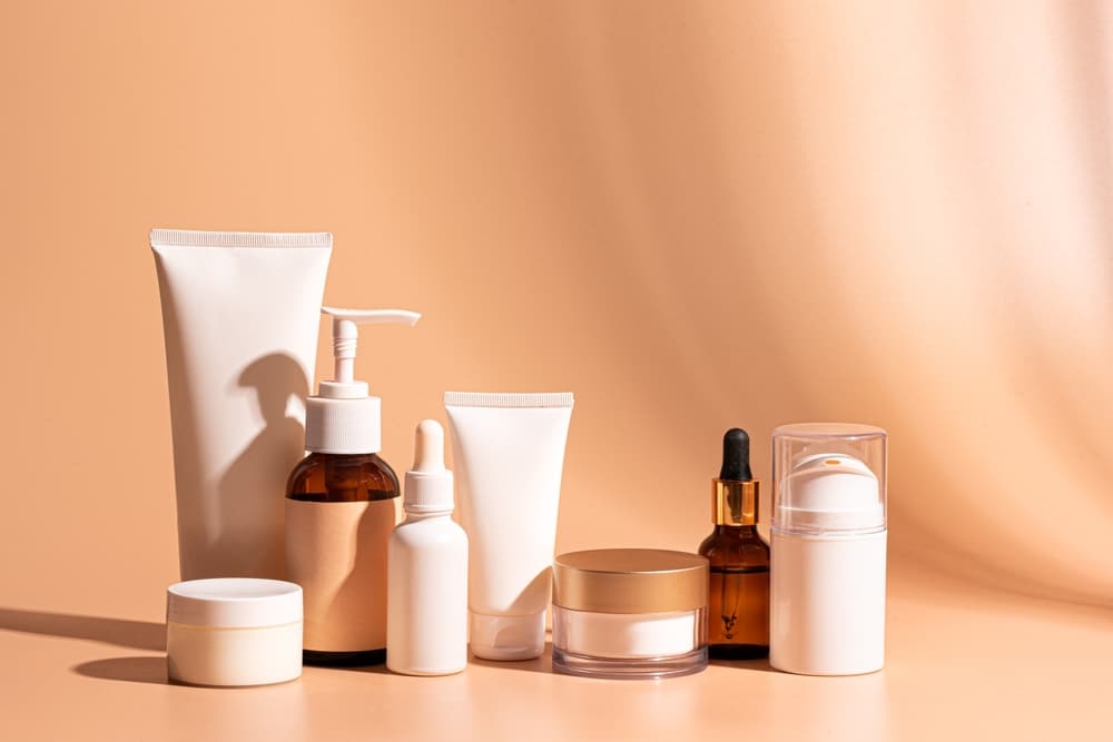 Various cosmetic products containers and bottles on beige orange background, copy space.